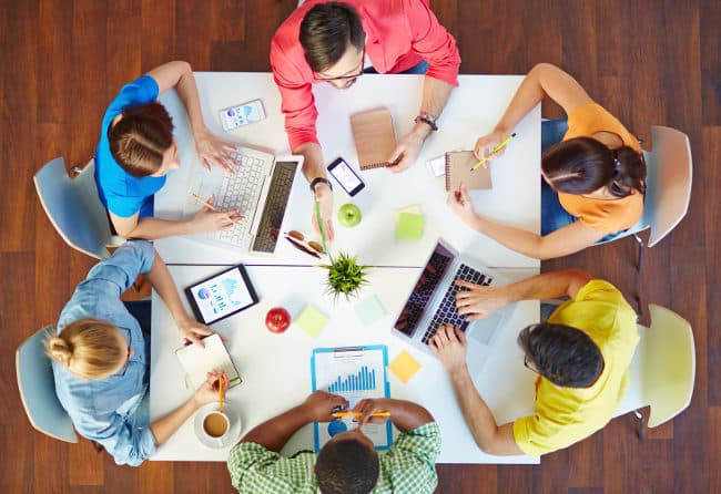 equipo de trabajo colaborando en una mesa con dispositivos y documentos de innovación en una PyME